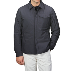 A man in a Montecore Dark Blue Light Down Waterproof Shirt Jacket and white pants stands against a plain background, showcasing contemporary outerwear at its finest.