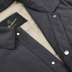 A close-up of the "Montecore" dark blue light down jacket shows a beige lining, collar, and silver snap buttons. This contemporary outerwear piece combines style and function akin to a classic waterproof shirt jacket.