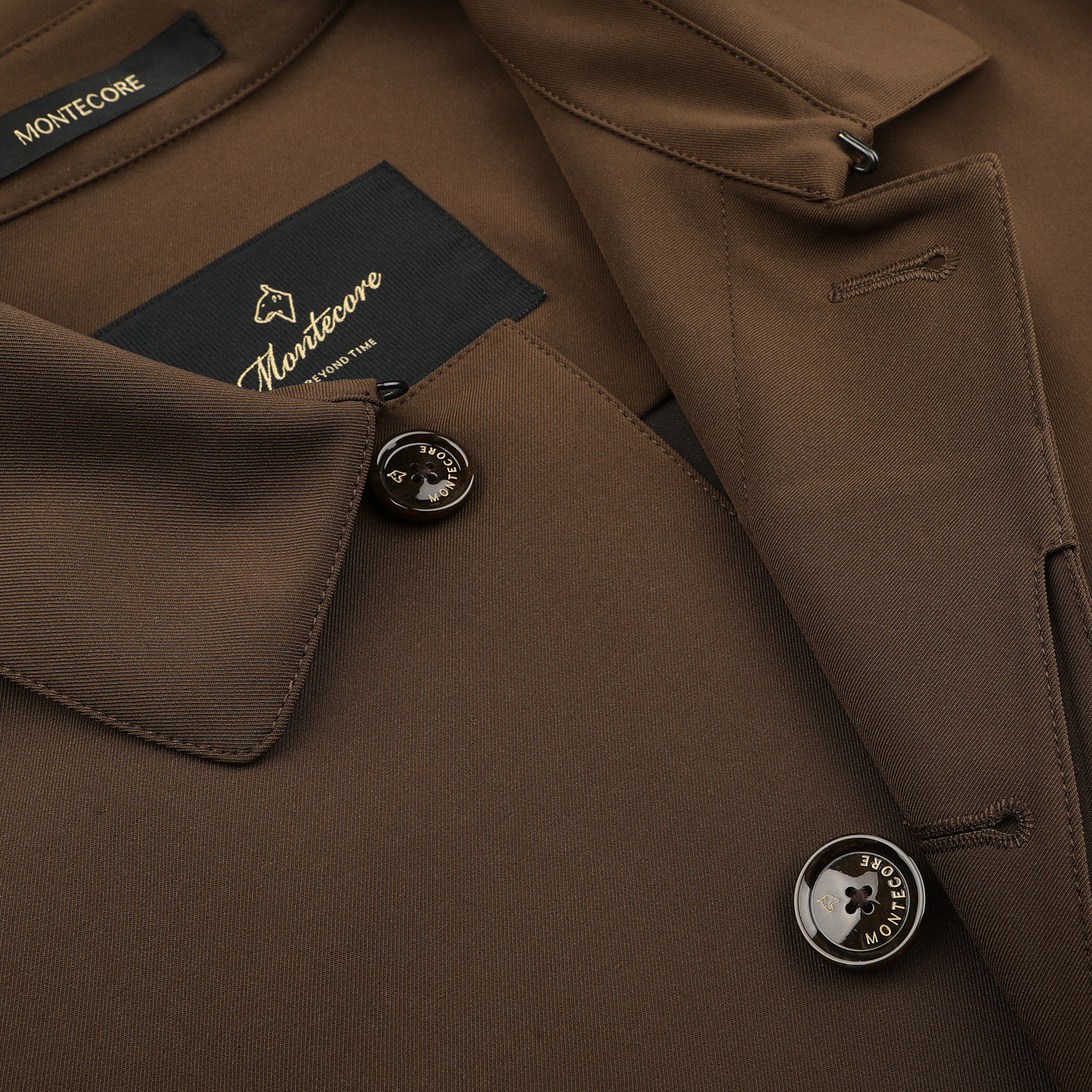 Close-up of a dark brown Aéro Twill Car Coat by Montecore, an Italian outerwear masterpiece, showcasing exquisite button details and a label inside the collar.