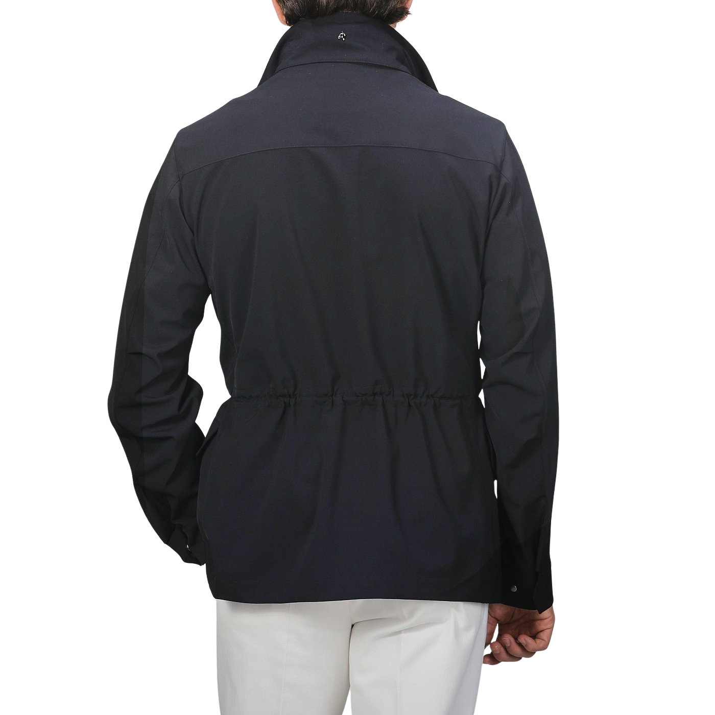 A rear view of a person wearing a Montecore Midnight Blue Aéro Twill Field Jacket, styled with crisp white pants, set against a plain background.