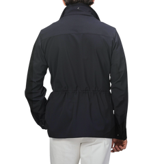 A rear view of a person wearing a Montecore Midnight Blue Aéro Twill Field Jacket, styled with crisp white pants, set against a plain background.