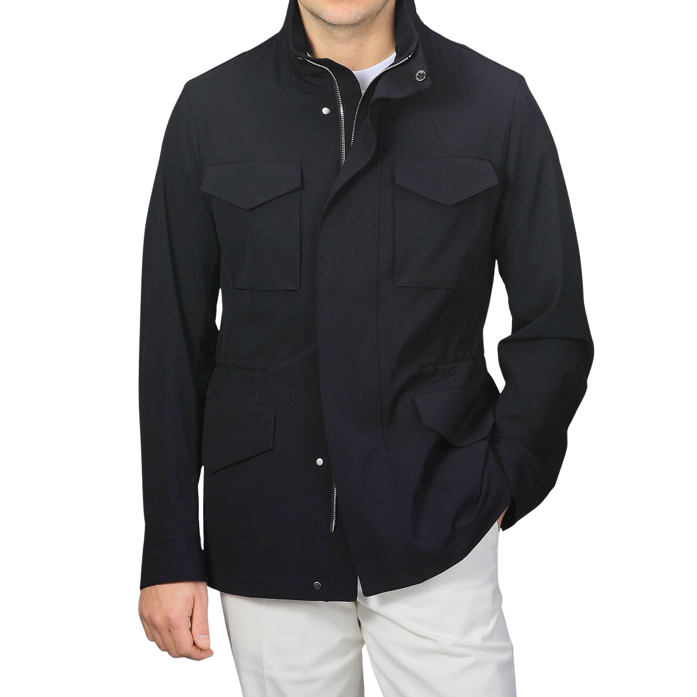 Wearing a Montecore Midnight Blue Aéro Twill Field Jacket made of technical nylon with four front pockets and white pants, a person stands against a plain background.