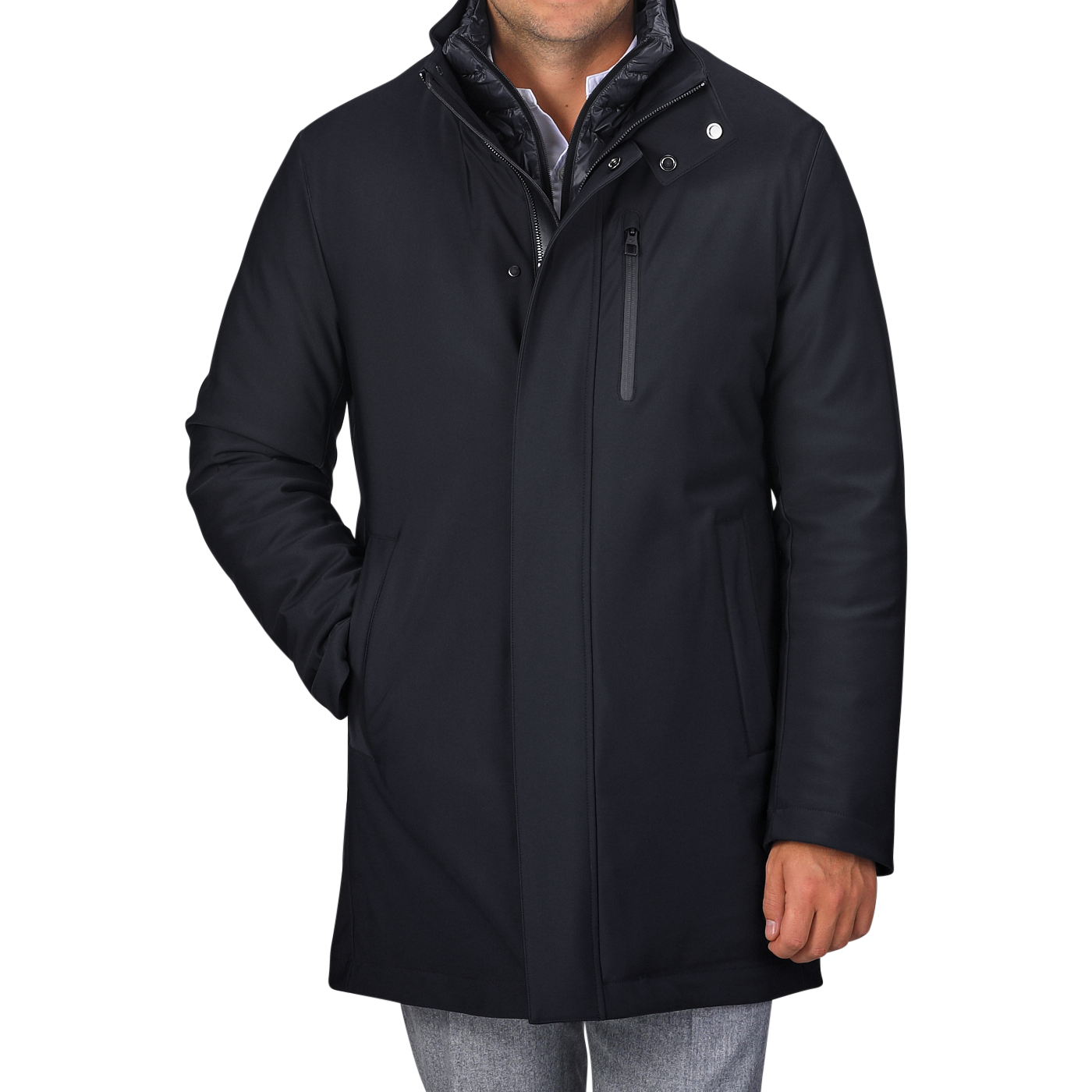 Rewritten Sentence:
A man in a Montecore Navy Blue Nylon Technical Padded Car Coat with a high collar and gray pants is standing with one hand in his pocket. The padded car coat features a front zipper, snap buttons, and a vertical chest pocket. The man's face is not visible.