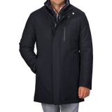 Rewritten Sentence:
A man in a Montecore Navy Blue Nylon Technical Padded Car Coat with a high collar and gray pants is standing with one hand in his pocket. The padded car coat features a front zipper, snap buttons, and a vertical chest pocket. The man's face is not visible.