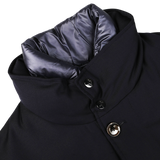 Close-up of a navy blue Montecore outerwear winter coat made from Super 120s wool with a high collar, showing detailed stitching, two buttons, and a partially visible gray inner lining.