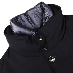 Close-up of a navy blue Montecore outerwear winter coat made from Super 120s wool with a high collar, showing detailed stitching, two buttons, and a partially visible gray inner lining.