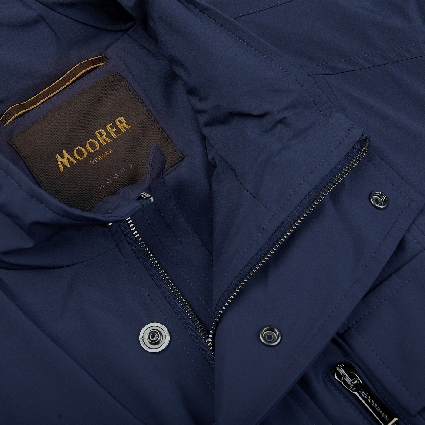 A close up of a water-resistant Dark Blue Lightweight Nylon Field Jacket with the word Moorer on it.