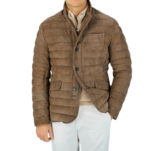 A man wearing a Moorer Dark Taupe Suede Leather Down Padded Jacket and white pants, showcasing craftsmanship.