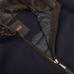 Close-up of a partially unzipped Moorer Navy Blue Cashmere Blend Down Padded Blouson with a brown fur-lined hood, revealing the inner lining and a visible brand label.