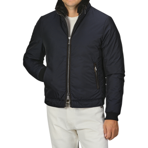 A man wearing the Moorer Navy Blue Nylon Down Padded Blouson with a zippered front and white pants. The jacket, resembling fine Italian outerwear, has a high collar and zippered pockets. The man's head is not visible.