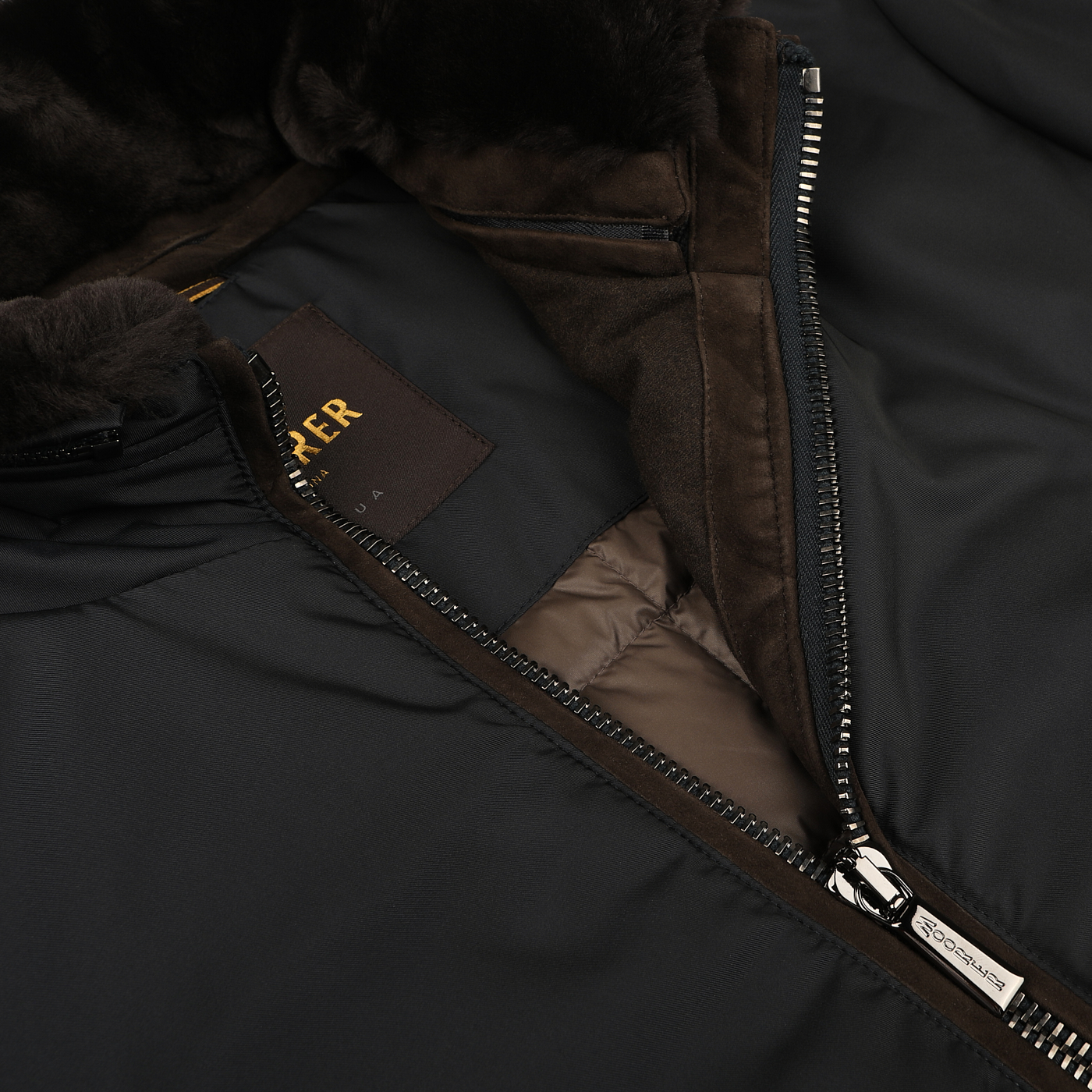 A close-up of a partially unzipped Navy Blue Nylon Down Padded Blouson from Moorer reveals its plush brown interior lining and branded tag, exemplifying Italian outerwear craftsmanship.