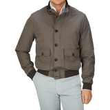 Man wearing a luxurious, olive green Moorer Technical Nylon Blouson with button detail over a light-colored shirt and pale pants.