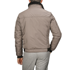 A person wearing a Taupe Beige Nylon Down Padded Blouson by Moorer and light grey pants, showcasing sleek Italian outerwear, is shown from the back.