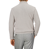 A person is seen from the back wearing a light taupe beige Morgano wool cashmere quarter-zip and gray pants.