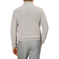 A person is seen from the back wearing a light taupe beige Morgano wool cashmere quarter-zip and gray pants.