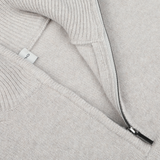 Close-up of a Morgano Taupe Beige Wool Cashmere Quarter Zip sweater with a metal zipper partially unzipped. A small white tag is visible on the inside, complementing the luxurious texture of cashmere.