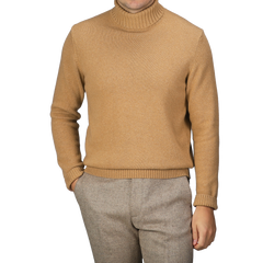 A person wearing a Camel Beige Heavy Wool Cashmere Rollneck by Morgano and gray pants, standing with hands in pockets against a plain background.