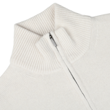 Close-up of the Morgano Cream Wool Cashmere Quarter Zip sweater, featuring a ribbed mock neck collar. The zipper is partially open, revealing a neatly stitched interior. The soft fabric hints at the luxury of its wool and cashmere blend.