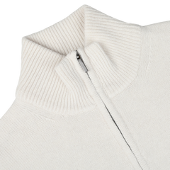 Close-up of the Morgano Cream Wool Cashmere Quarter Zip sweater, featuring a ribbed mock neck collar. The zipper is partially open, revealing a neatly stitched interior. The soft fabric hints at the luxury of its wool and cashmere blend.