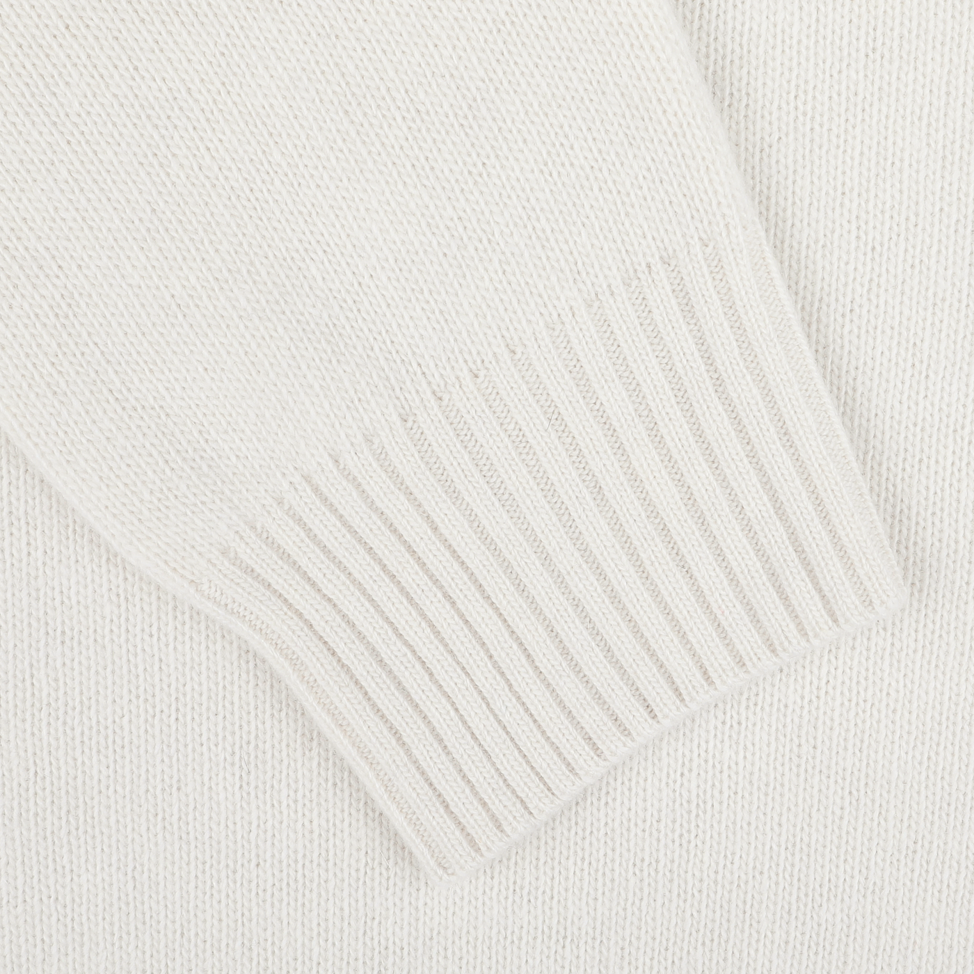 Close-up of a cream knitted fabric, highlighting the ribbed texture on the edge of this luxurious Morgano Cream Wool Cashmere Quarter Zip sweater.