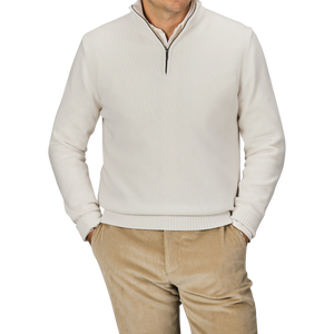 A person wearing a Cream Wool Cashmere Quarter Zip by Morgano and beige corduroy pants stands with hands in pockets against a plain background.