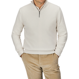 A person wearing a Cream Wool Cashmere Quarter Zip by Morgano and beige corduroy pants stands with hands in pockets against a plain background.