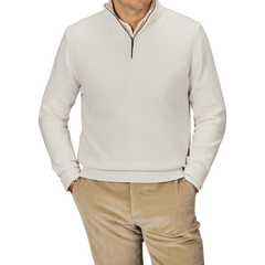 A person wearing a Cream Wool Cashmere Quarter Zip by Morgano and beige corduroy pants stands with hands in pockets against a plain background.