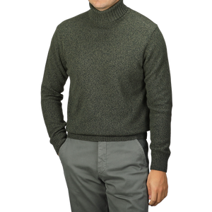 A person wearing a Green Melange Heavy Wool Cashmere Rollneck by Morgano and gray pants, with hands in pockets.