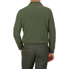 Rear view of a person wearing the Morgano Moss Green Wool Cashmere Quarter Zip and gray pants. The high-collared Italian knitwear drapes elegantly, with the person's hand resting by their side.