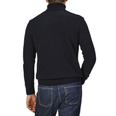 A person wearing a Morgano Navy Blue Heavy Wool Cashmere Rollneck sweater and blue jeans, standing with their back facing the camera.