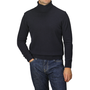 A person wearing a Morgano Navy Blue Heavy Wool Cashmere Rollneck and blue jeans stands with one hand in a pocket.