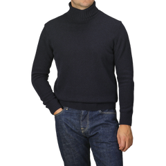 A person wearing a Morgano Navy Blue Heavy Wool Cashmere Rollneck and blue jeans stands with one hand in a pocket.