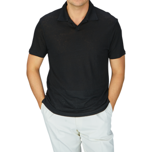 A man wearing a breathable Paige Black Linen Capri Collar Polo Shirt and white linen pants.