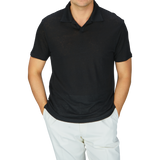 A man wearing a breathable Paige Black Linen Capri Collar Polo Shirt and white linen pants.