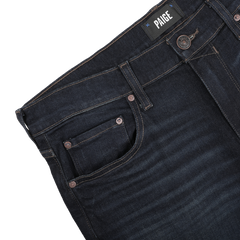 Close-up of dark blue denim Blue Faded Cotton Cramer Normandie Jeans featuring a visible "Paige" label on the waistband, showcasing front pocket and button details. These straight-leg jeans incorporate a hint of cotton stretch, providing comfort and style throughout the day.