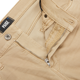 Close-up of Caramel Beige Cotton Transcend Federal Slim Jeans with a partially open zipper and button. The brand label "Paige" is visible above the pocket, showcasing the comfortable fit and luxurious Transcend fabric.