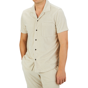 A person wearing a Cream Beige Cotton Towelling Polo Shirt by Paige with a front pocket and matching pants stands against a plain gray background.
