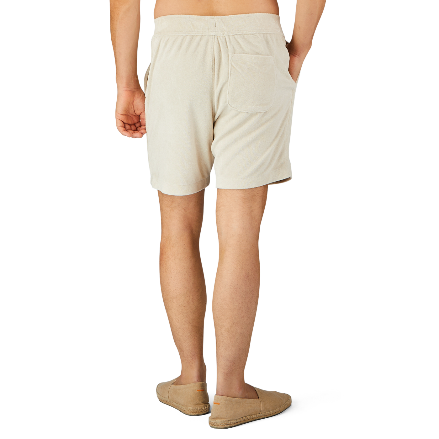 Back view of a person wearing Paige's Cream Beige Cotton Towelling Shorts with a drawstring waist and beige slip-on shoes, standing against a light gray background.