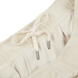 Close-up image of a beige garment, Cream Beige Cotton Towelling Shorts made from a soft towelling cotton blend by Paige, with an adjustable drawstring waist featuring metal aglets.