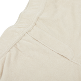 Close-up view of a beige fabric with a seam and an overlapping flap, displaying a soft texture, perfect for summer shorts crafted from a towelling cotton blend. The Cream Beige Cotton Towelling Shorts by Paige exemplify this ideal material.