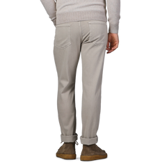 An individual is seen from behind, dressed in Paige's Moroccan Clay Cotton Transcend Federal Slim Jeans paired with a cozy, light-colored sweater.