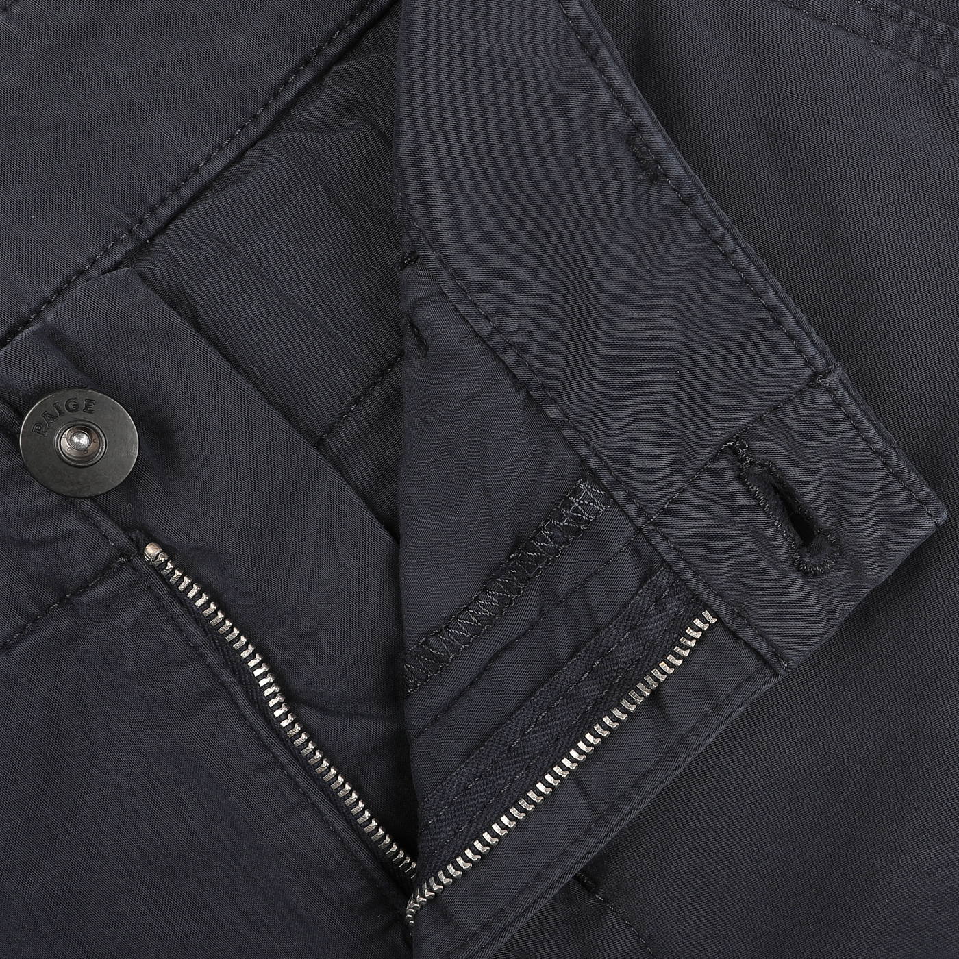 A close-up of a navy blue design highlights a button with "Paige" inscribed on it and a partially visible zipper, suggesting the comfortable fit of the Danford cotton chinos.