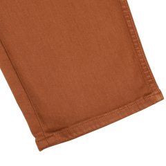 Close-up of the hem of Paige's Rust Brown Cotton Transcend Federal Slim Jeans. The stitching is visible along the bottom edge, showcasing a comfortable fit.