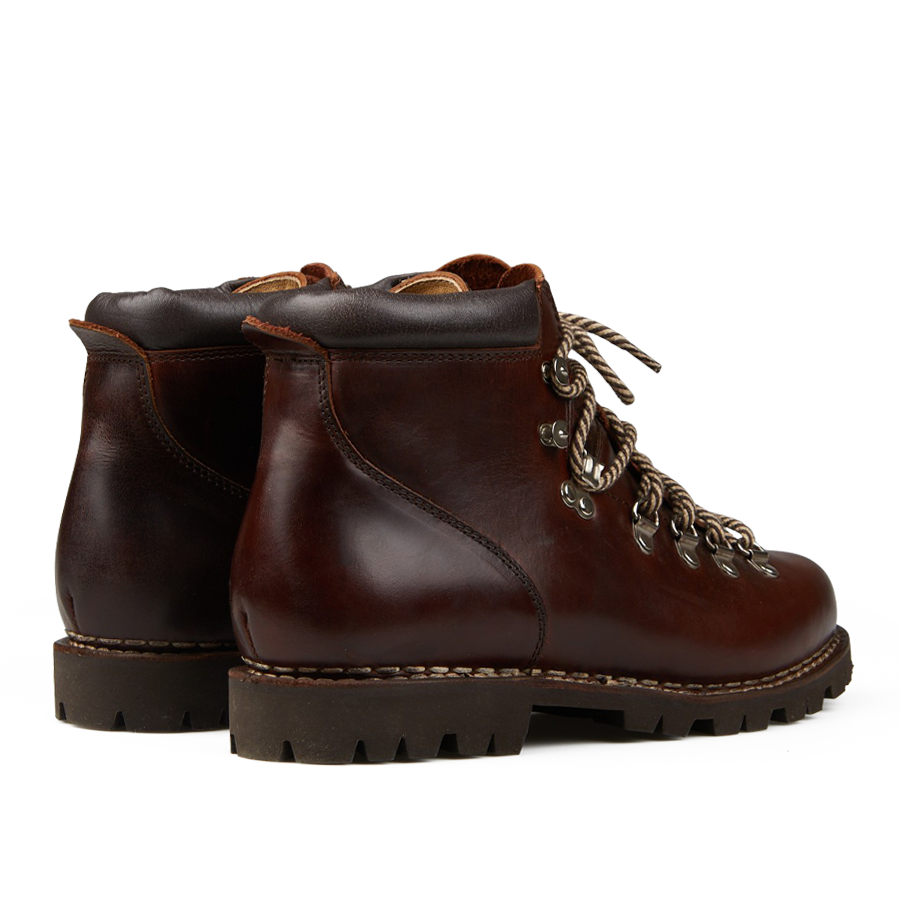 The Marron Lis Ecorce Leather Avoriaz Hiking Boot by Paraboot is made from dark brown calf leather and showcases black padded collars, silver eyelets, and bold red and white laces. The design is finished with a robust commando rubber sole to ensure maximum traction for any adventure.