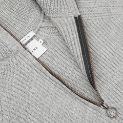 Close-up of a light gray Peregrine Ford zip-neck sweater, showcasing premium British knitwear. The sweater features a visible tag and open zipper, highlighting the luxurious merino wool construction.