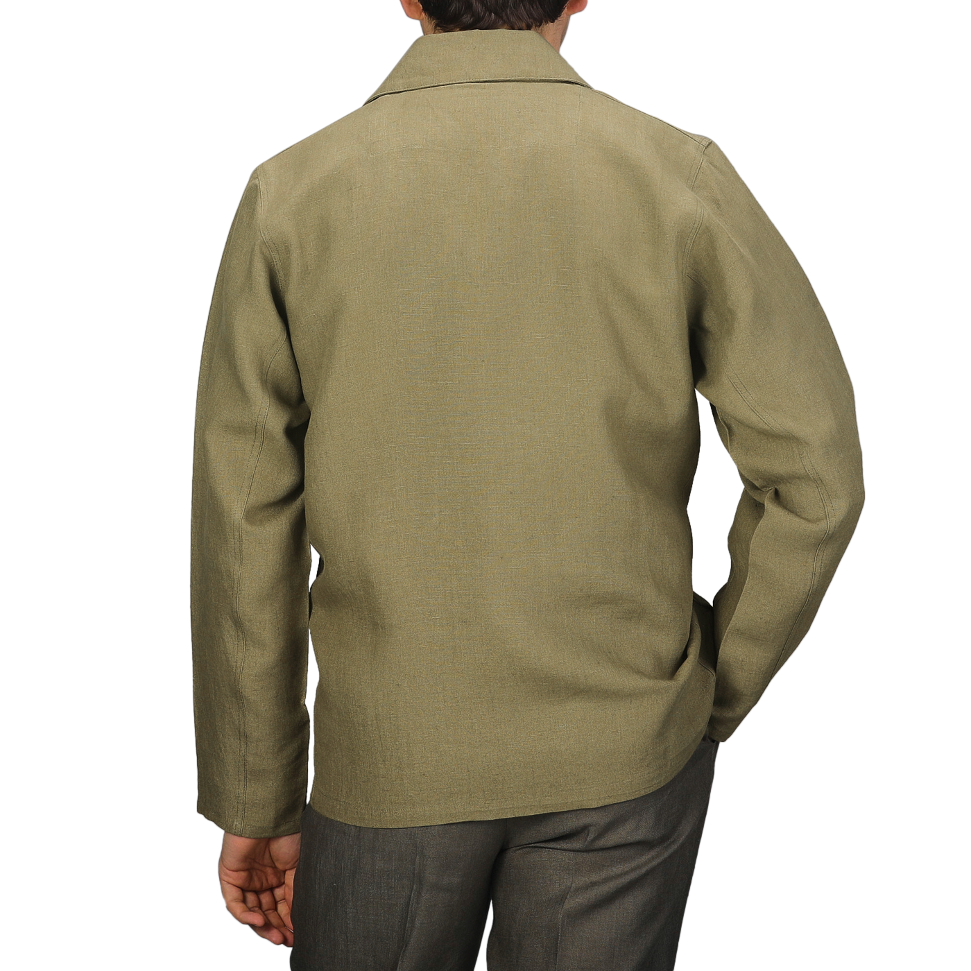 Wearing a Khaki Green Linen Grange Shacket by Peregrine, a person stands against a gray backdrop, showcasing understated style from behind.