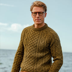 A man wearing a Peregrine Khaki Green Merino Wool Hudson Jumper sweater.