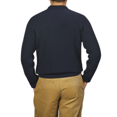 A person is shown from the back, wearing a Navy Blue Wool Ford Raglan Crewneck by Peregrine and beige pants, with their hands in their pockets.