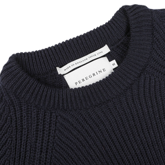 Close-up of a navy blue wool Ford raglan crewneck showing a "Peregrine" label and a tag indicating "Made in England since 1796," exemplifying premium British knitwear.