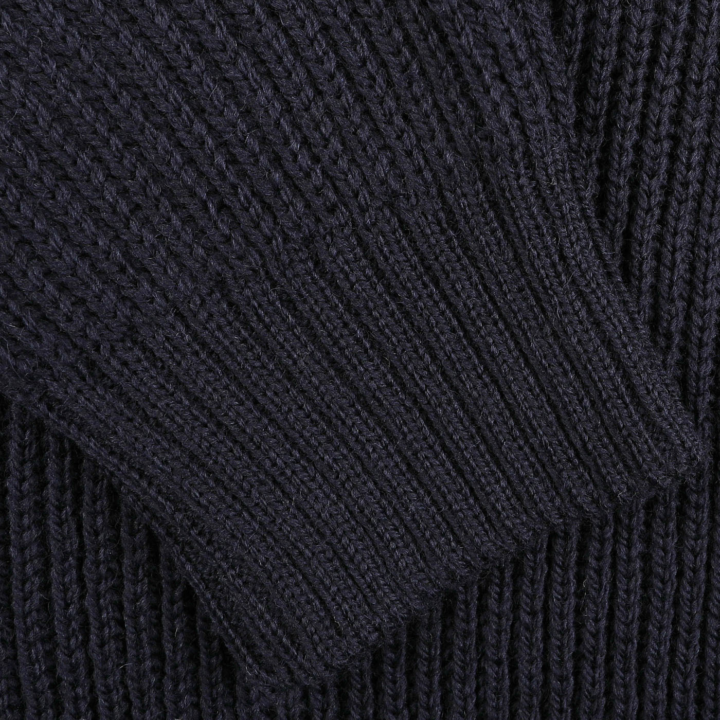 Close-up of a dark-colored, ribbed knit fabric from a Navy Blue Wool Ford Raglan Crewneck by Peregrine, showing detailed texture and pattern.